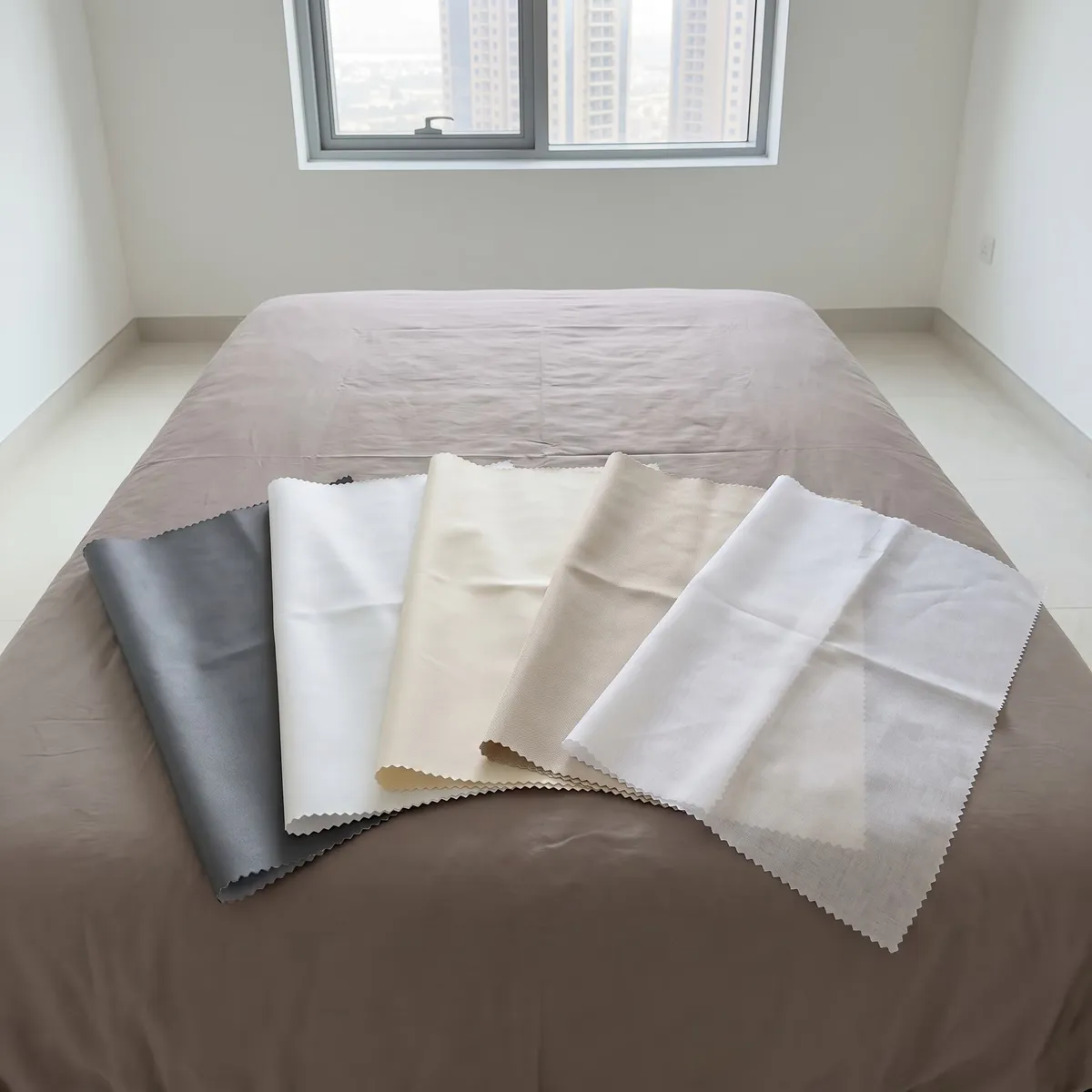 Five lining samples with zig-zag edges fanned across a grey-taupe bed, from dark grey through white, cream and beige to a thin white one