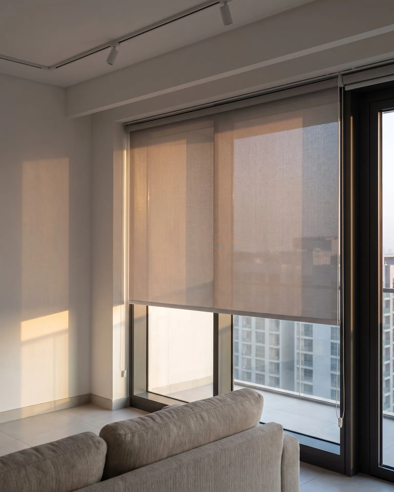 Roller blind half lowered against afternoon sun in a Dubai apartment living room