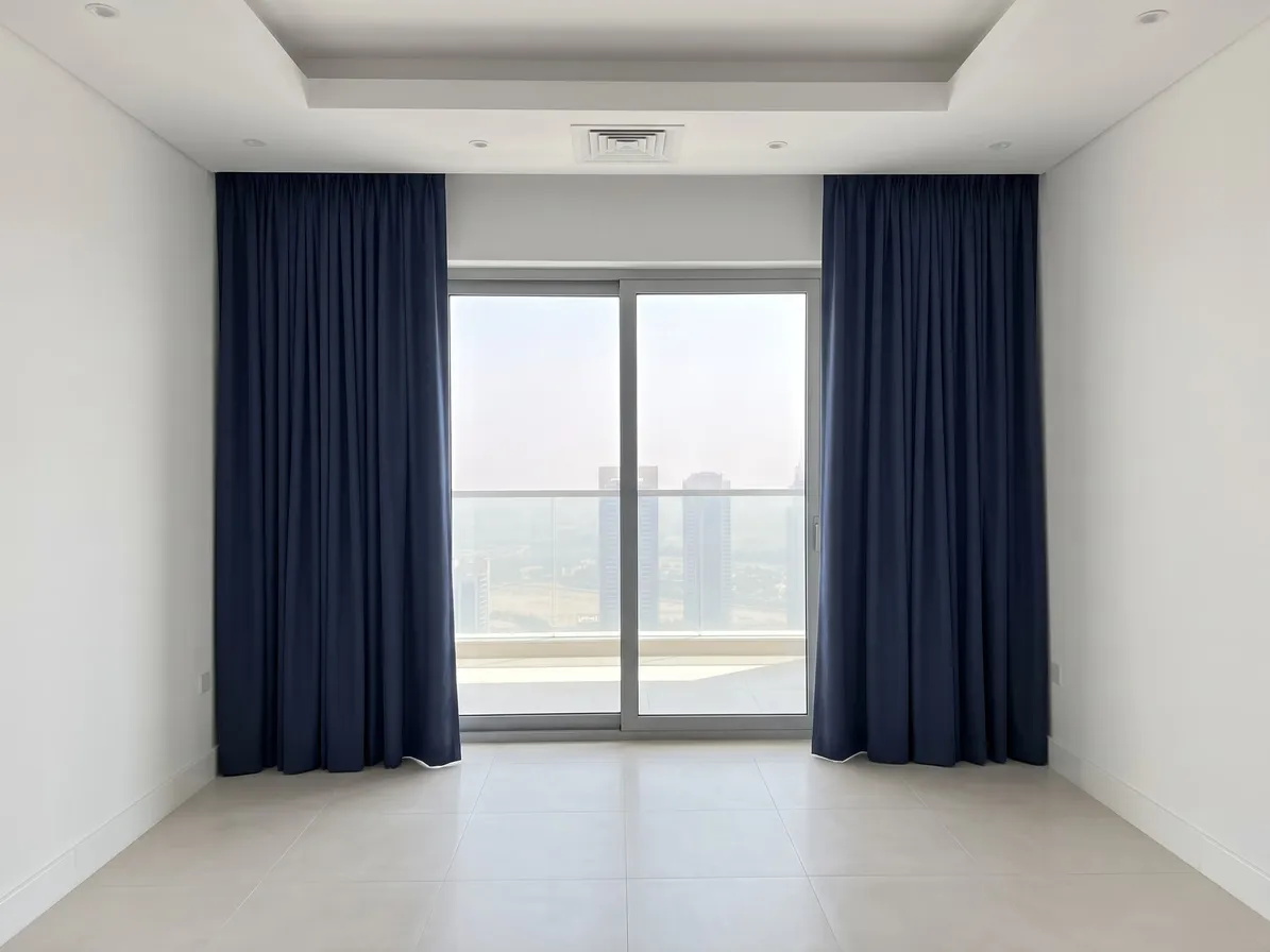 Navy curtains hanging from a slim ceiling cove, drawn open at both sides of a sliding balcony door, towers beyond the railing