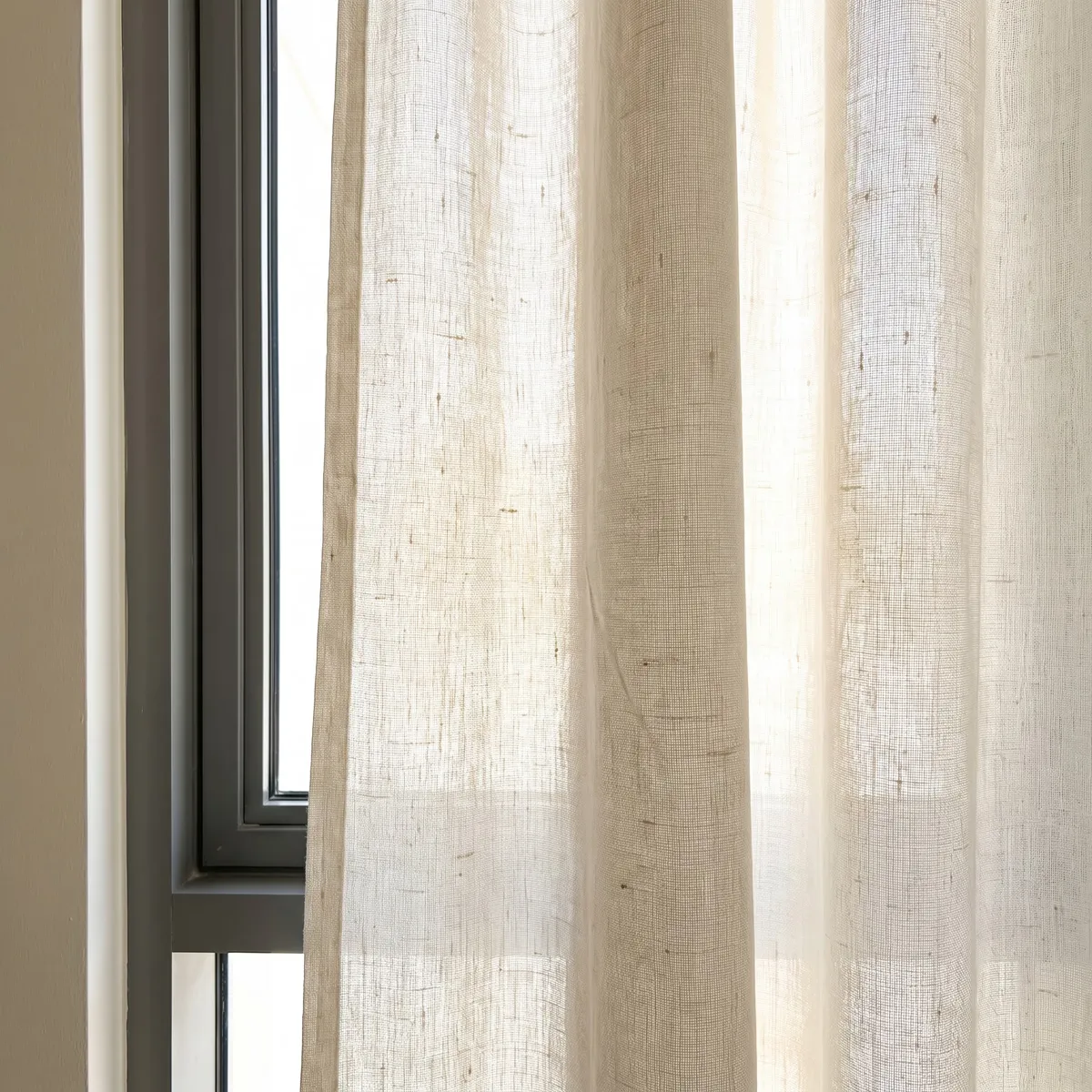 Close-up of cream linen against a bright window, thicker slub threads and the open weave lit from behind