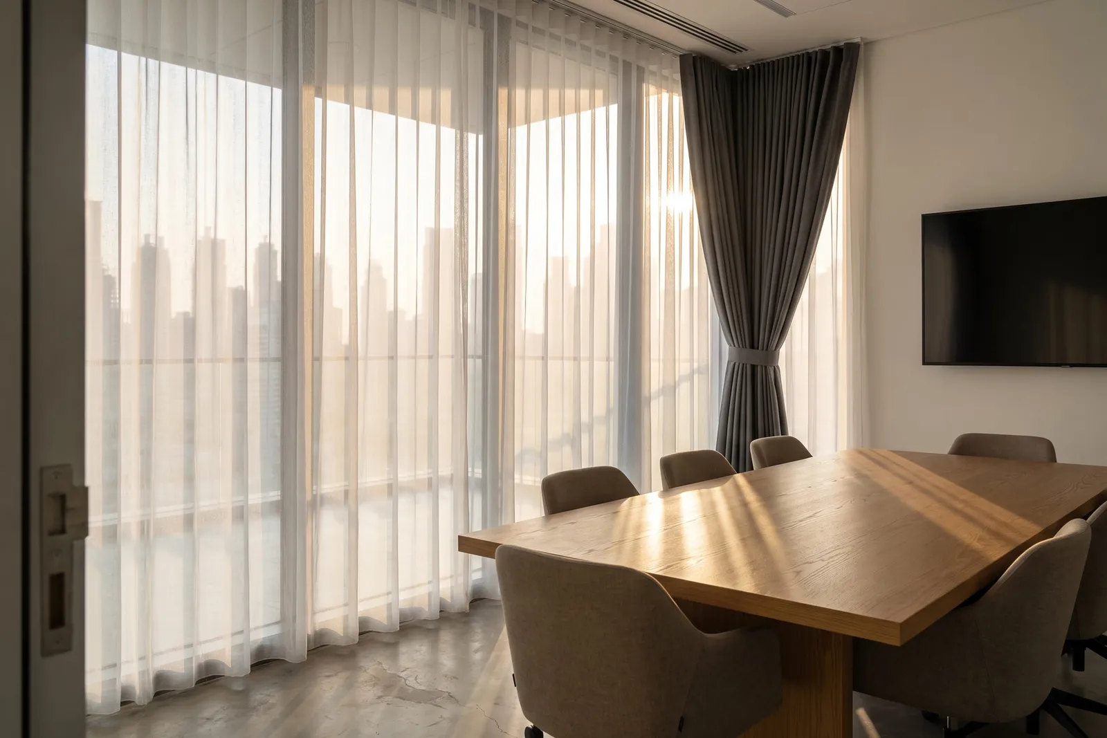 Office curtains in a Dubai meeting room: a sheer along the sunlit glass wall, a charcoal curtain at one end