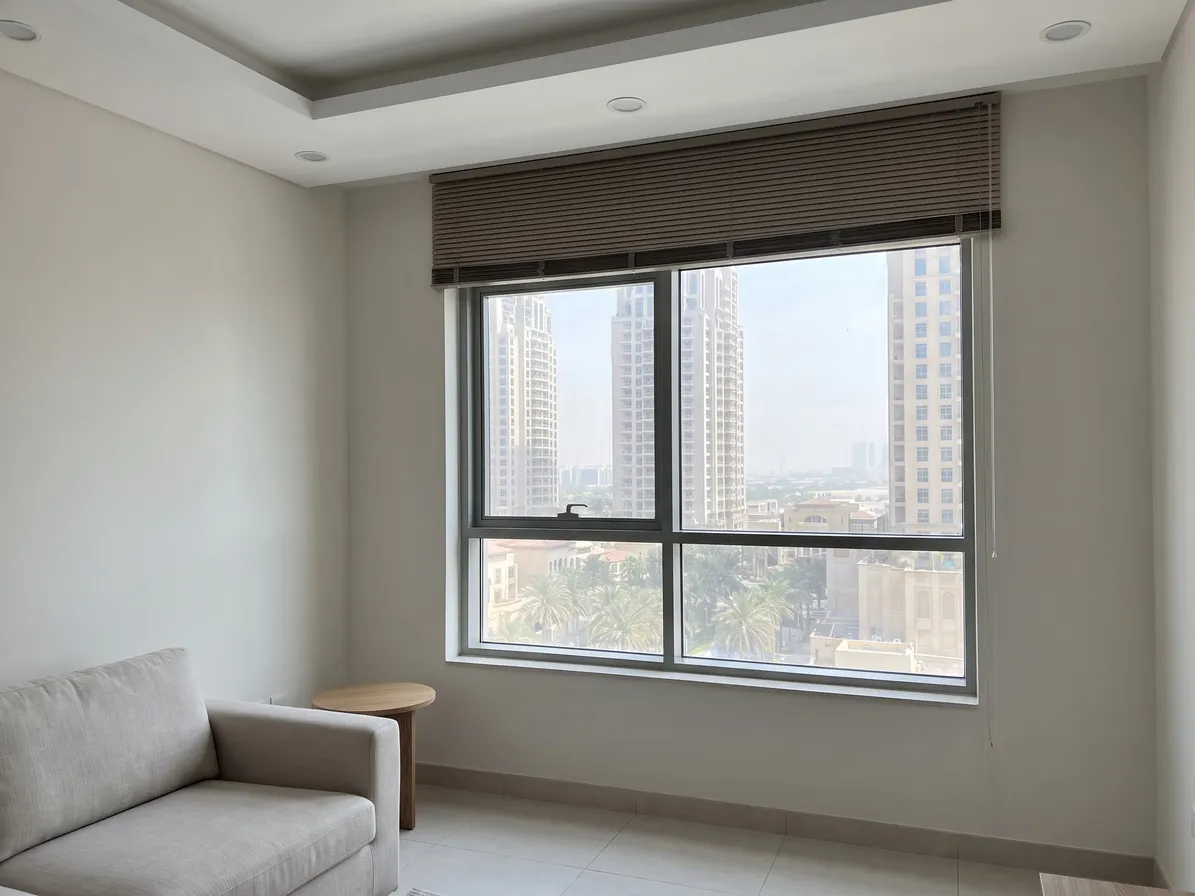 Taupe Venetian blind raised on the wall above a two-pane window, its slats gathered in a band above the frame and the glass clear